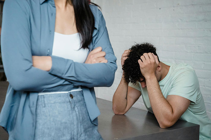 Man frustrated with girlfriend's nagging, sitting in a basement with head in hands.