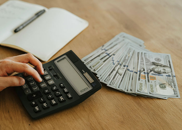 Calculating rent contributions with a calculator and cash on a wooden table, highlighting family financial planning.