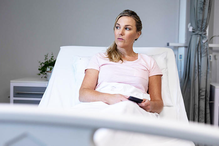 Woman in a hospital bed looking concerned while holding a remote, relating to a marriage issue.