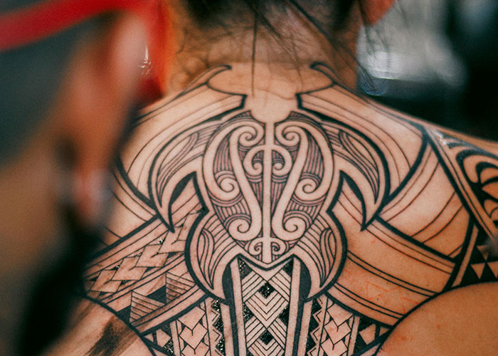 Intricate back tattoo design with geometric patterns and bold lines, illustrating ideas to consider before getting inked.