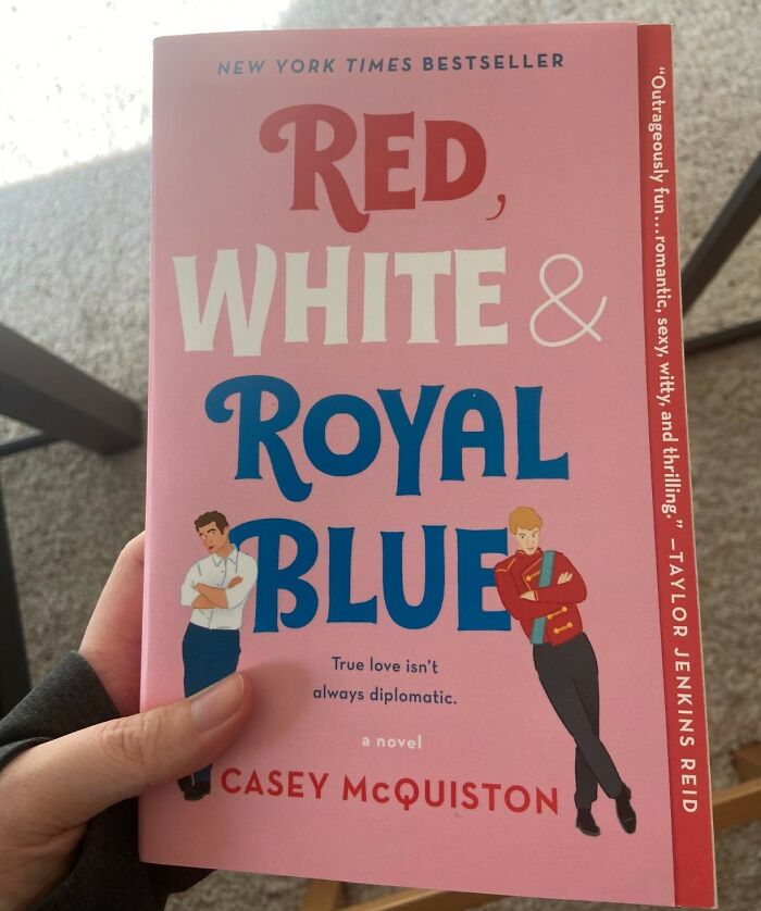 Cover of "Red, White & Royal Blue" romantic book held in hand.