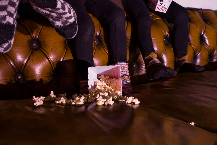 Socks on a couch with spilled popcorn, capturing a worst first date moment.