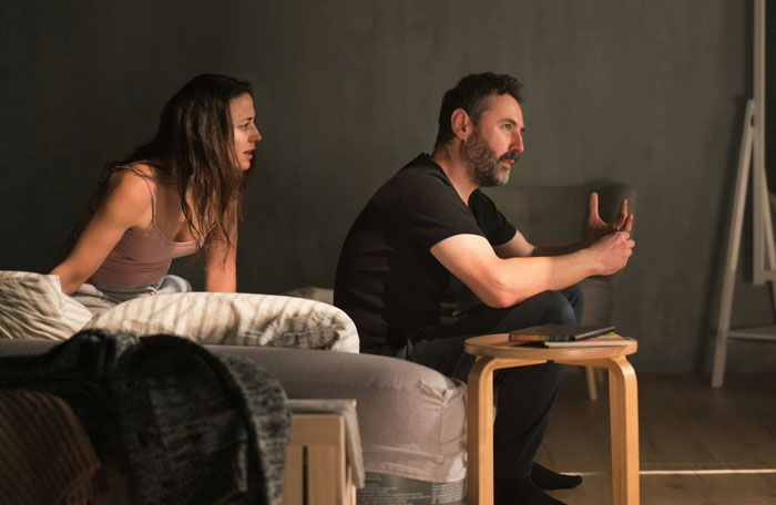 Man and woman having a serious conversation at home, discussing reasons for allegedly leaving children alone.