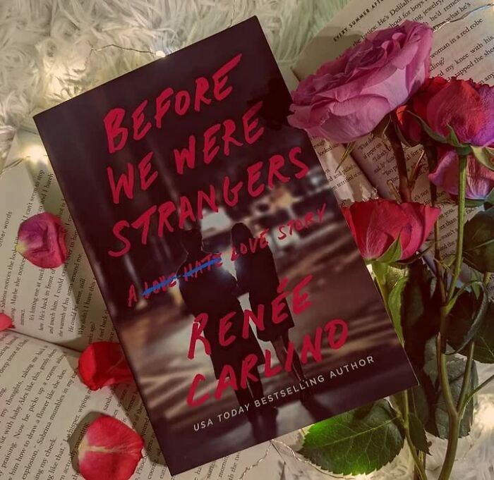 Romantic book "Before We Were Strangers" surrounded by pink roses and open pages.