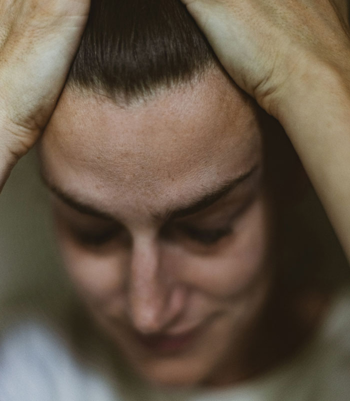 Woman with a stressed expression, hands on head, related to the keyword "husband denies leaving children home alone.