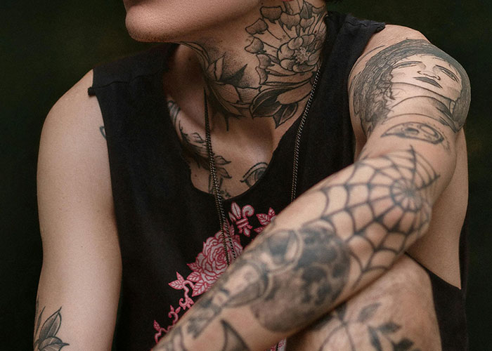 Person with tattoos on neck and arm, showing intricate designs, relevant to getting inked decisions.