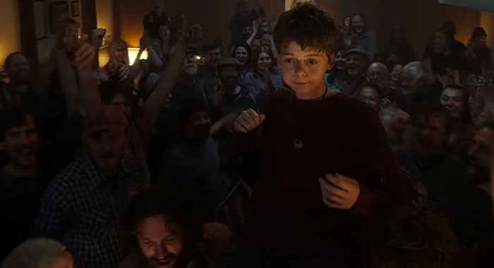 Child being lifted by cheering crowd, celebrating in a jubilant scene related to the 28 Years Later cast.