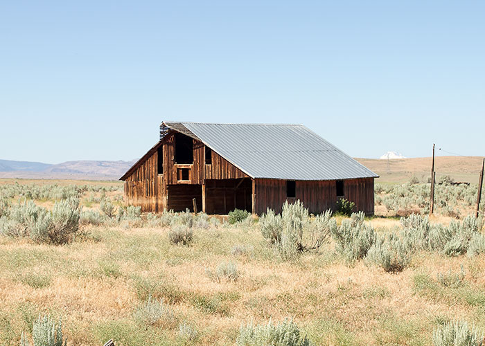 An old wooden barn in a remote field, suggesting a haunting atmosphere often found on scary hikes.