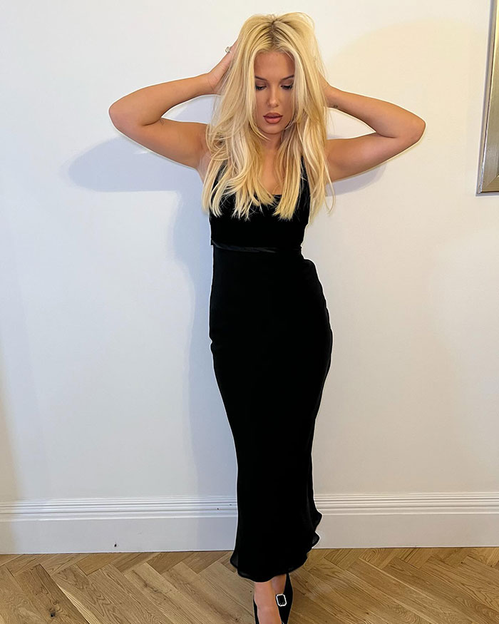 Blonde woman in a sleek black dress, posing with hands on head, showcasing a bold look for her 21st birthday celebration.