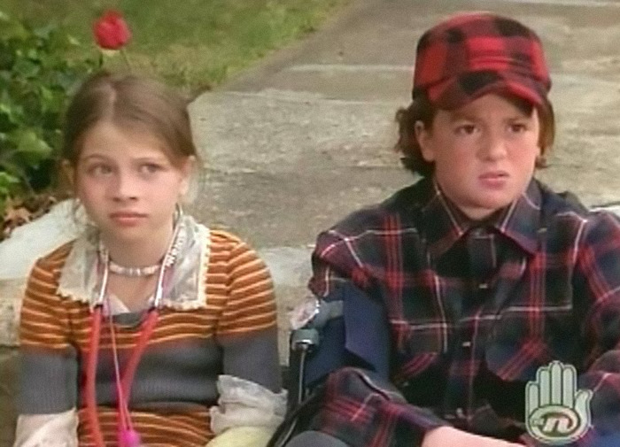 Child actors in a Nickelodeon scene, wearing casual clothes, conveying a thoughtful moment outdoors.