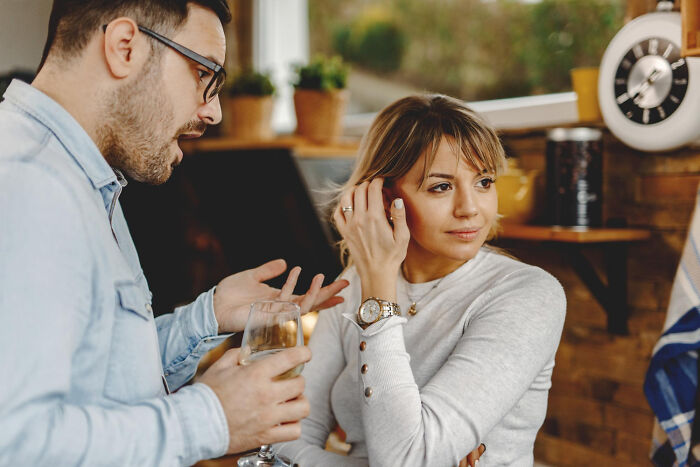 Man talking while woman seems disinterested during a first date in a cozy cafe setting.