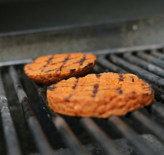 Vegan burgers grilling on a barbecue, highlighting vegan lifestyle at family gatherings.