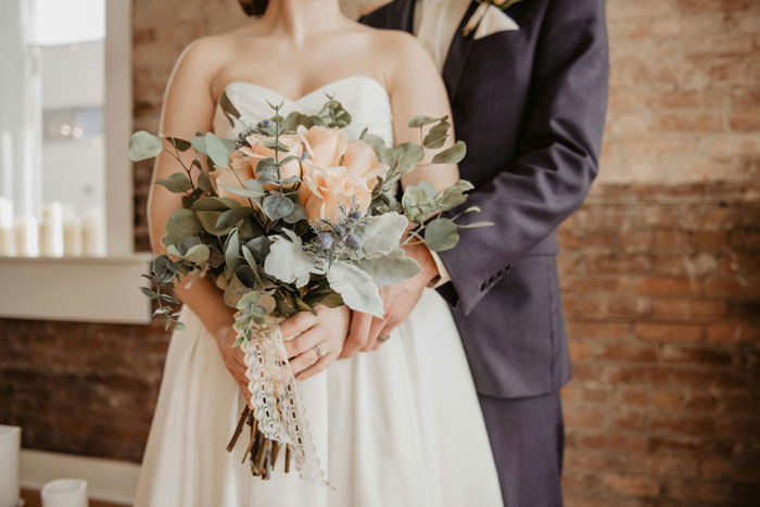 Bride holding bouquet in wedding dress, embracing groom, signifying a significant event.