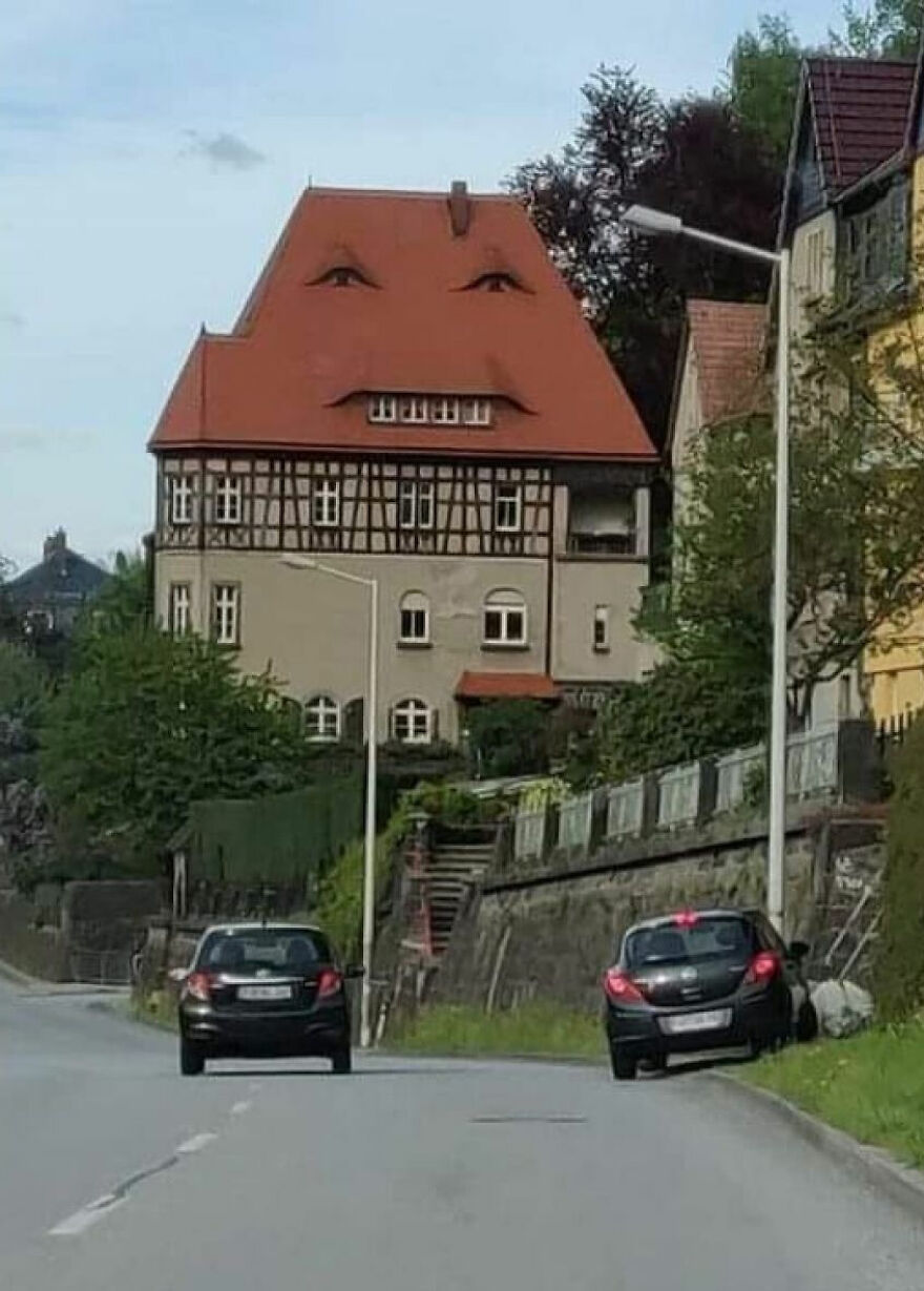 Unusual architecture with house resembling a face, featuring eyes in roof design.