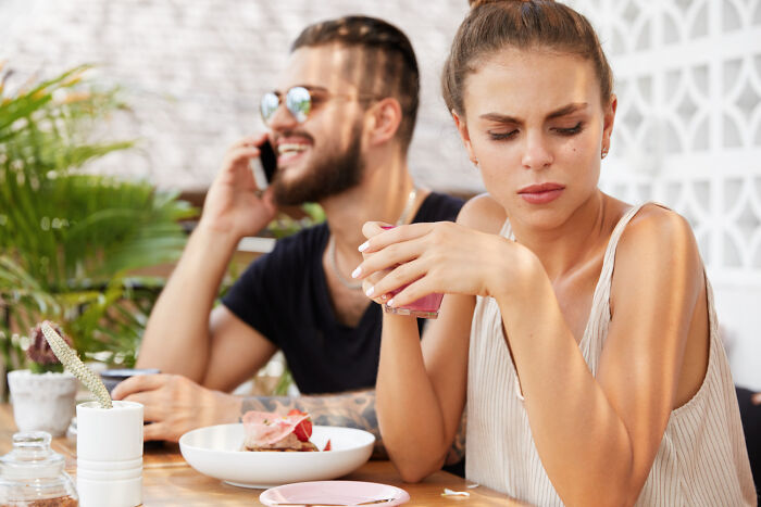 Woman looking upset on a first date as man talks on phone, illustrating worst first date experience.