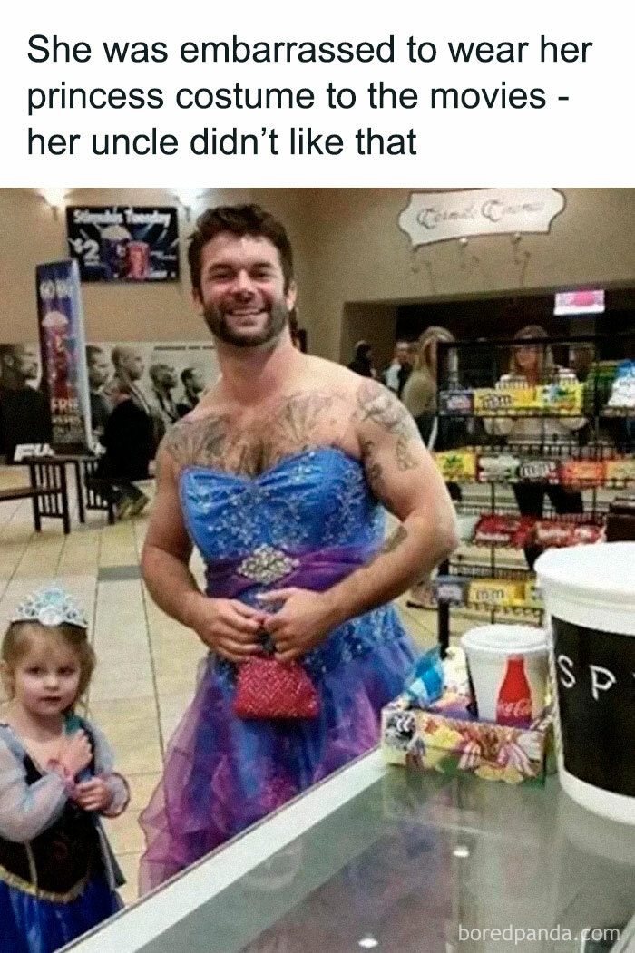 Man in a blue princess dress with a child in a similar costume at a movie theater, bringing joy with heartwarming humor.