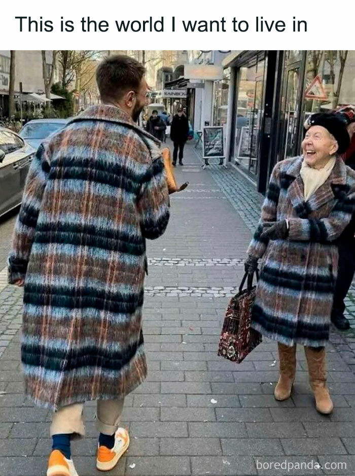 Man and elderly woman in matching coats, smiling joyfully on a city street.