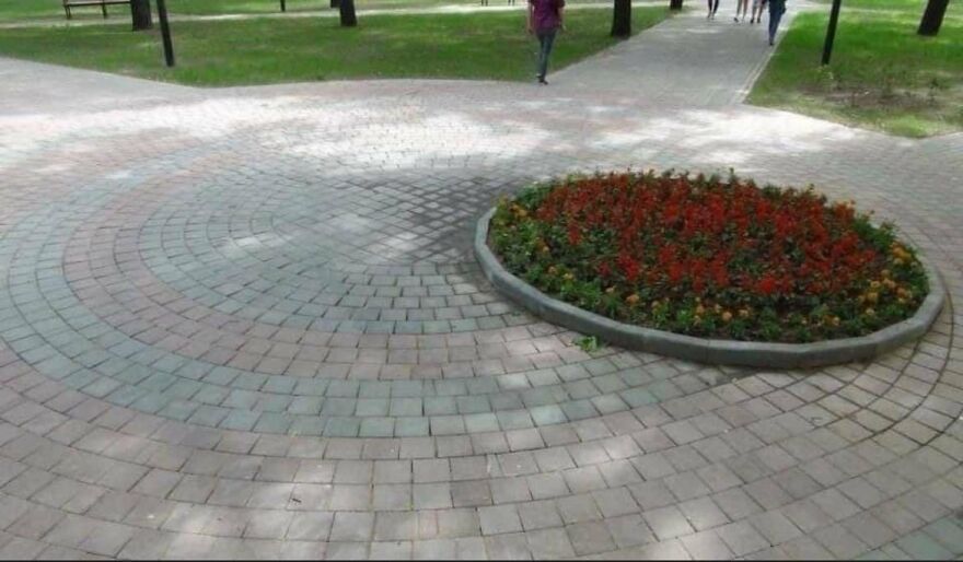 Circular brick pathway with misplaced flowerbed, highlighting architecture shaming.