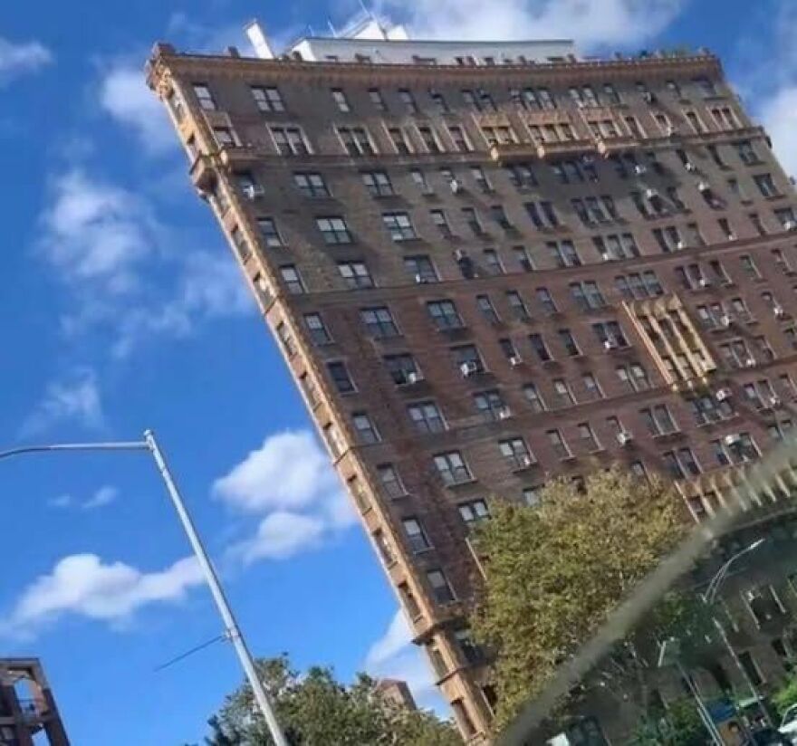 Unusual architectural design of a slanted, flat-faced building against a blue sky.