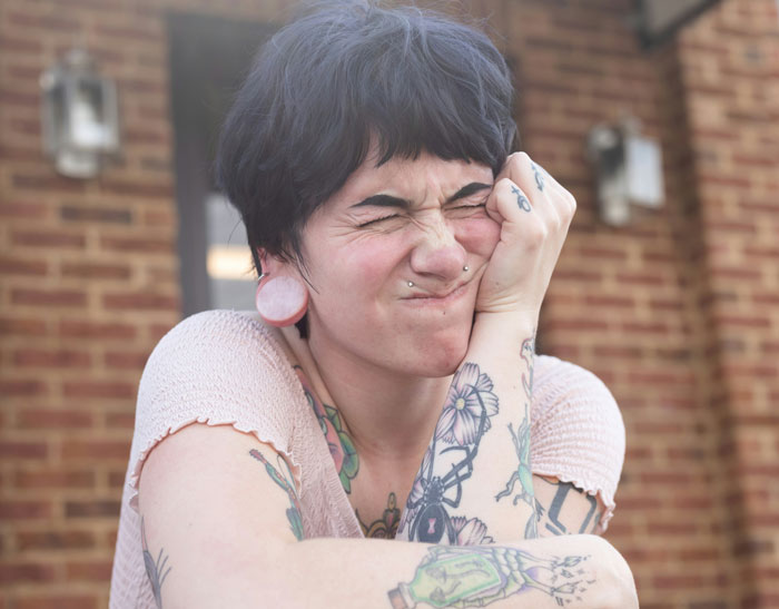 Tattooed woman looking frustrated outside, related to vegan family conflict.