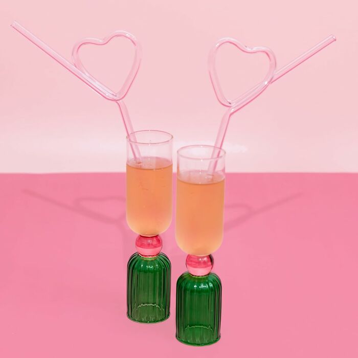 Two colorful drinks with heart-shaped straws on a pink background, perfect Galentines Day gifts for celebrating friendship.