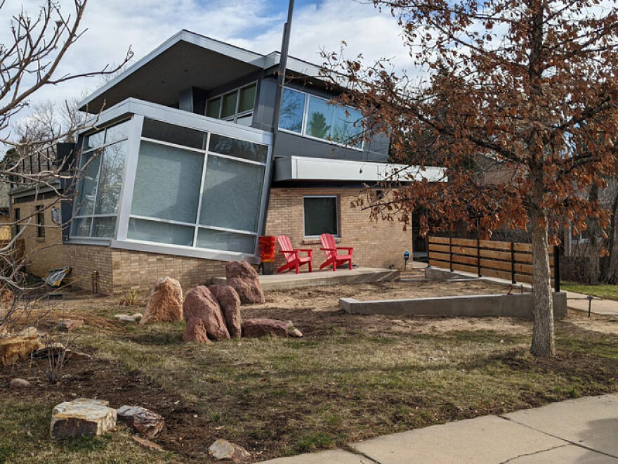 Modern house with unusual architecture, featuring slanted windows and a mix of brick and metal design elements.