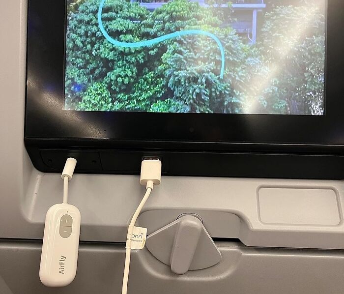 In-flight entertainment screen with adapter, showcasing things worth spending money on for a better travel experience.