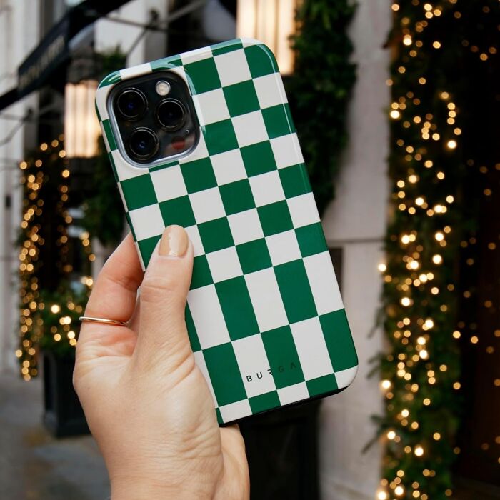 Green and white checkered phone case, held in hand, with festive lights in the background, highlighting spending money on style.