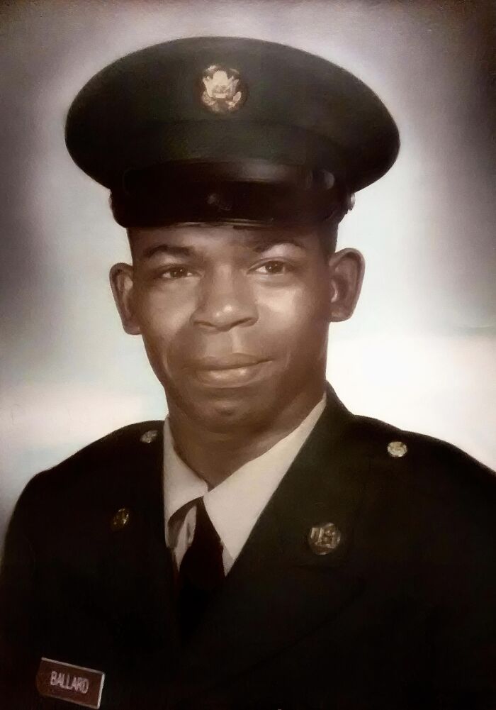 A rare historical photo of a uniformed soldier with a name tag, wearing a formal cap and smiling slightly.