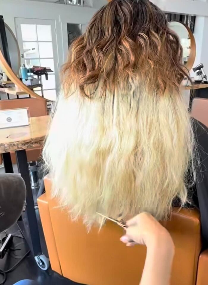 A stylist working on a two-toned hair color fail in a salon setting.