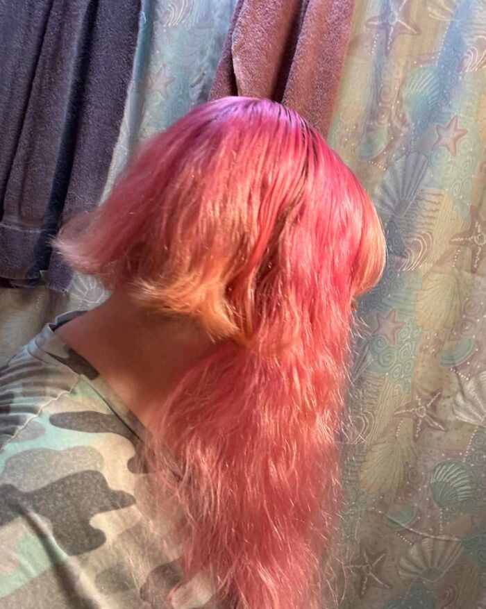 Pink hair fail with uneven cut, showcasing a wavy texture in a bathroom setting.