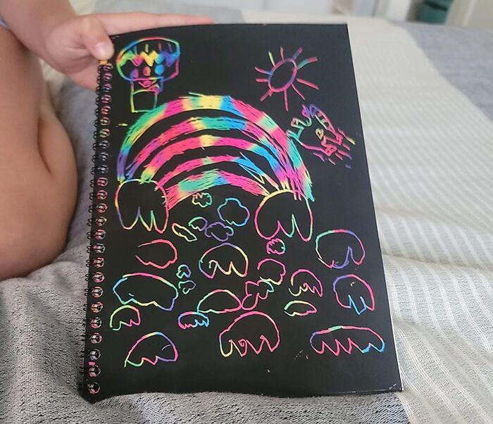 Child holding a colorful scratch art drawing, a popular Valentine's Day gift for kids.