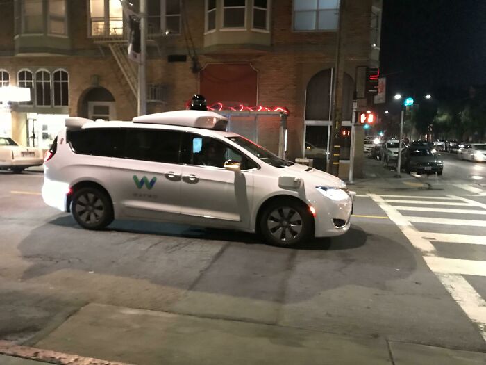 Autonomous vehicle at night in cityscape, representing "boomer complaints" about modern technology.