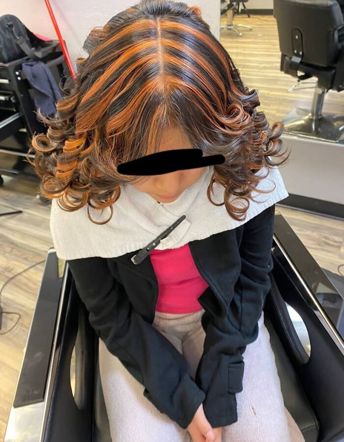 Person with curled hair featuring uneven orange and black highlights, a hair fail example.