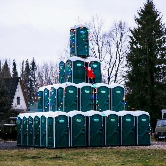 Unique garden decoration with stacked porta-potties forming a pyramid, adorned with colorful lights.