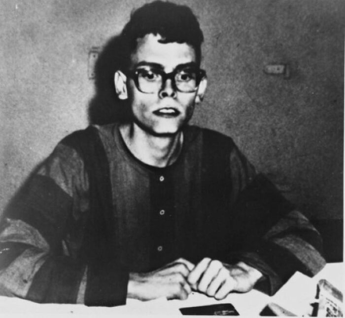 Man in striped shirt and glasses sitting at a table, sharing interesting facts.