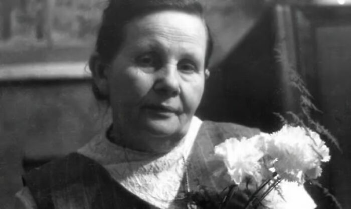 An elderly woman holding white flowers, symbolizing interesting facts shared by people.