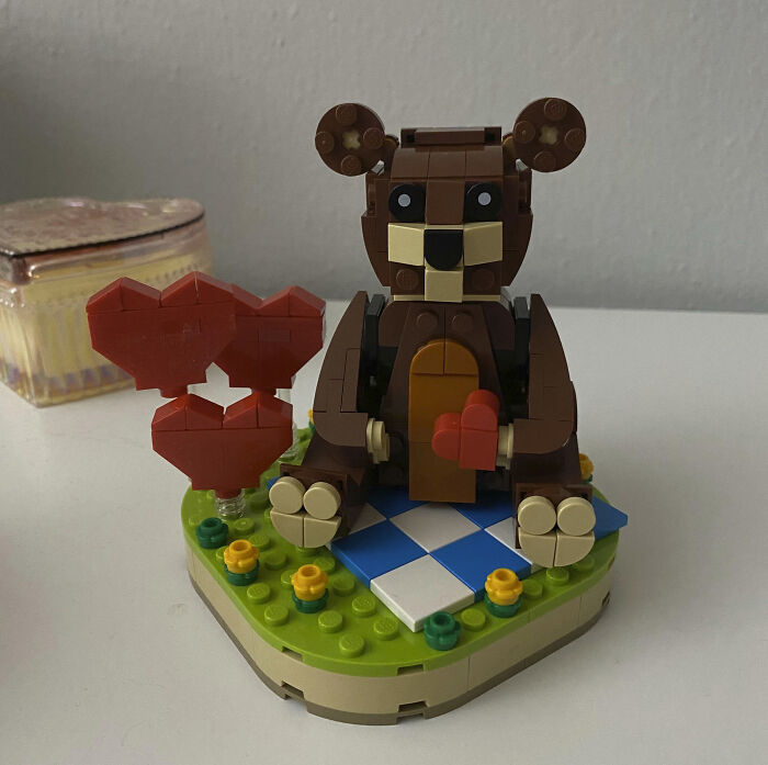 LEGO bear holding a red heart on a grassy base, ideal for cute Valentine's Day gifts.