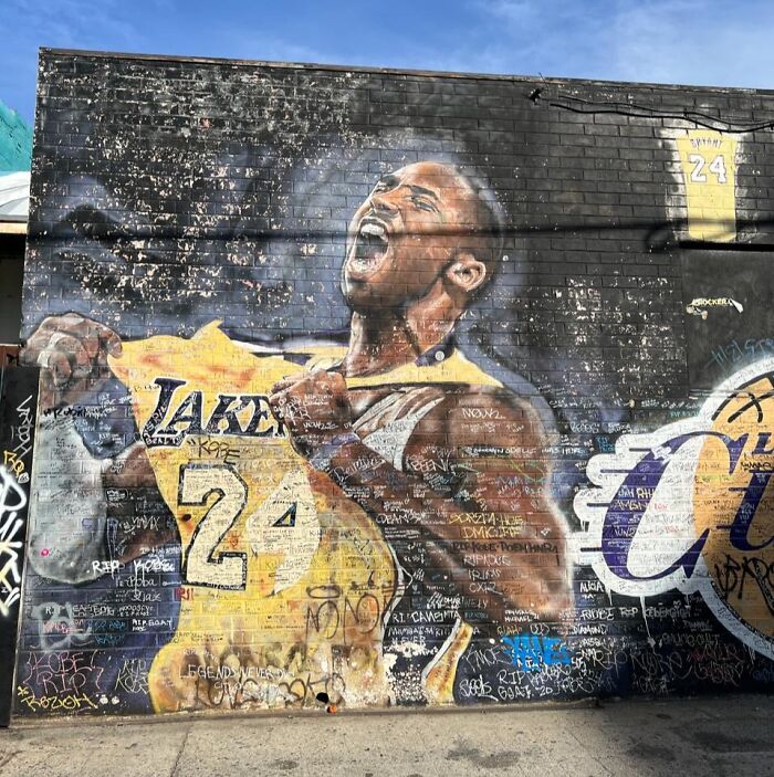 Mural of basketball player in Lakers jersey gripping shirt, surrounded by graffiti, capturing a powerful mic-drop moment.