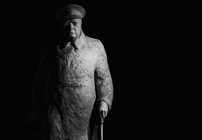 A statue of a historical figure in uniform, captured dramatically in low light, representing iconic mic-drop moments.