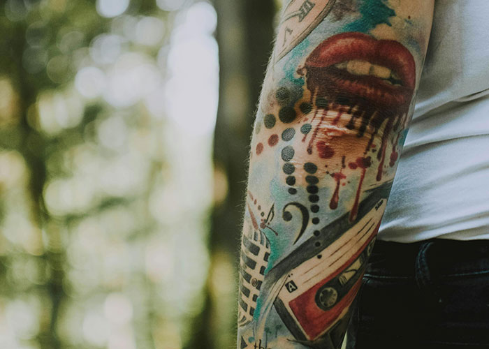 Arm with creative tattoo design, highlighting colorful ink art in natural light.