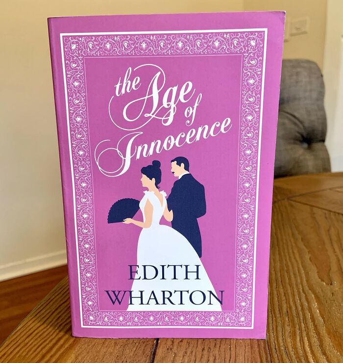 Pink cover of "The Age of Innocence" by Edith Wharton, featuring an illustrated couple. Romantic books theme.