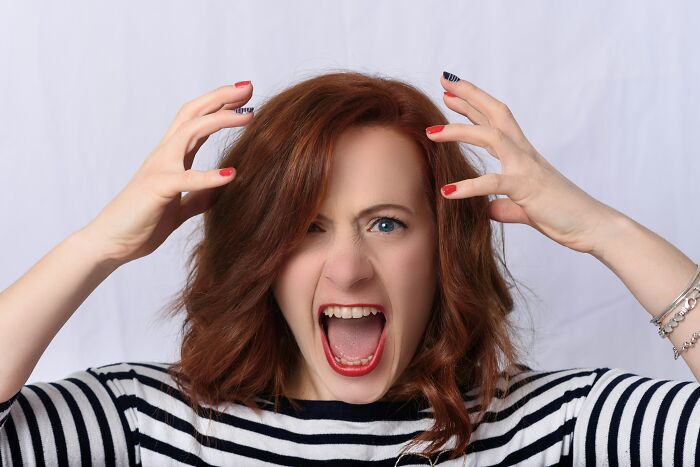 A woman in a striped shirt looks frustrated, expressing emotions.