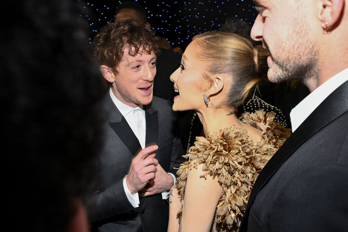 Guests at Critics Choice Awards in conversation, elegant attire, twinkling background.