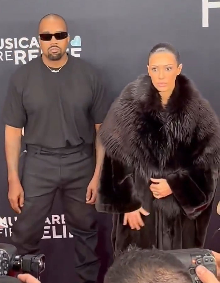 Two individuals pose at the event, one in a black shirt and pants, and the other in a luxurious fur coat, "Indecent Exposure".