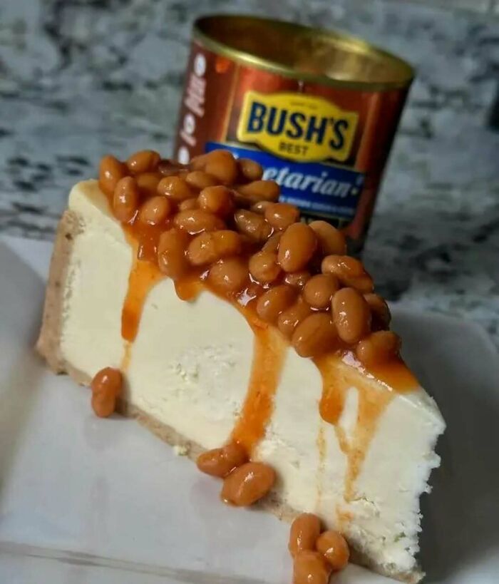 Slice of cheesecake topped with baked beans, showcasing an unusual cooking meme.