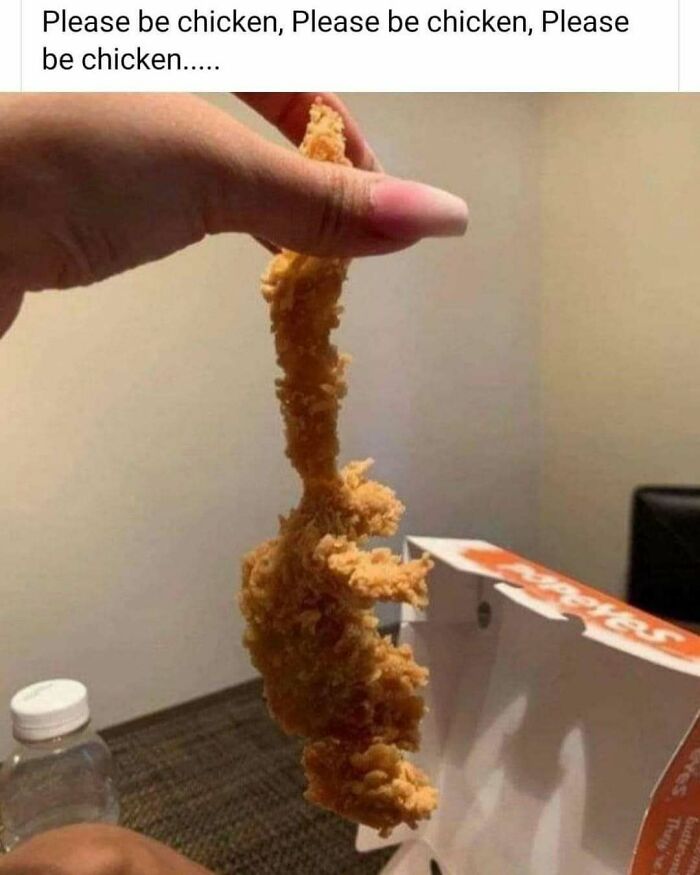 Hand holding a fried piece of food resembling a strange shape, with a fast-food box in the background. Cooking humor meme.