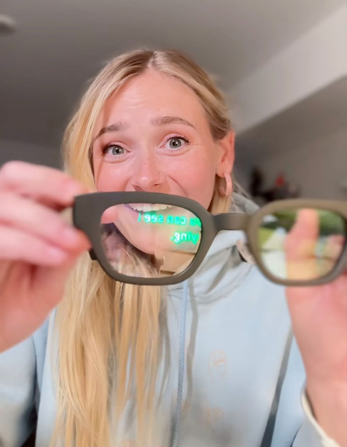 A girl holding glasses with projected text, showcasing her excited reaction to seeing spoken words visually for the first time.