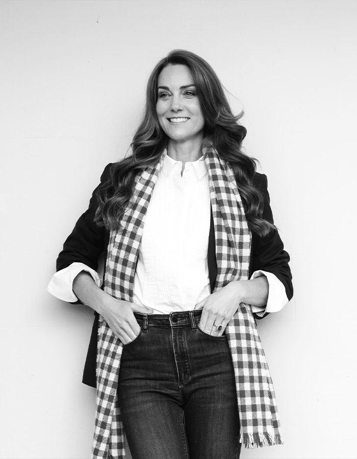 Woman wearing a checkered scarf and blazer, smiling, related to fashion policy.