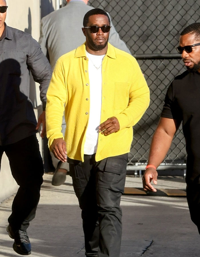 Man in yellow jacket and sunglasses walking with others, related to lawyer quitting as trial approaches.